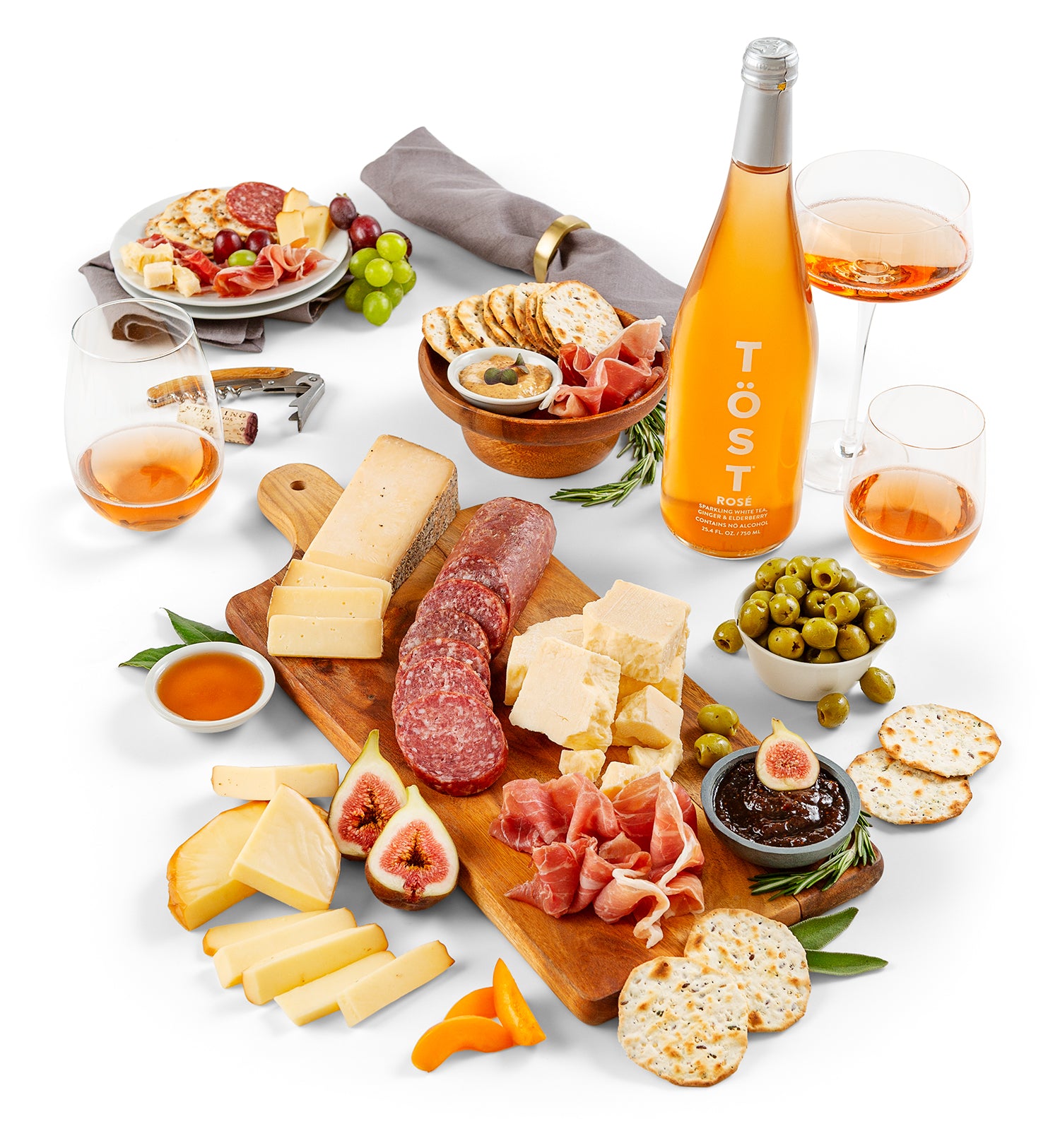Assorted meats, cheeses, and fruits with a bottle of Töst wine on a white background