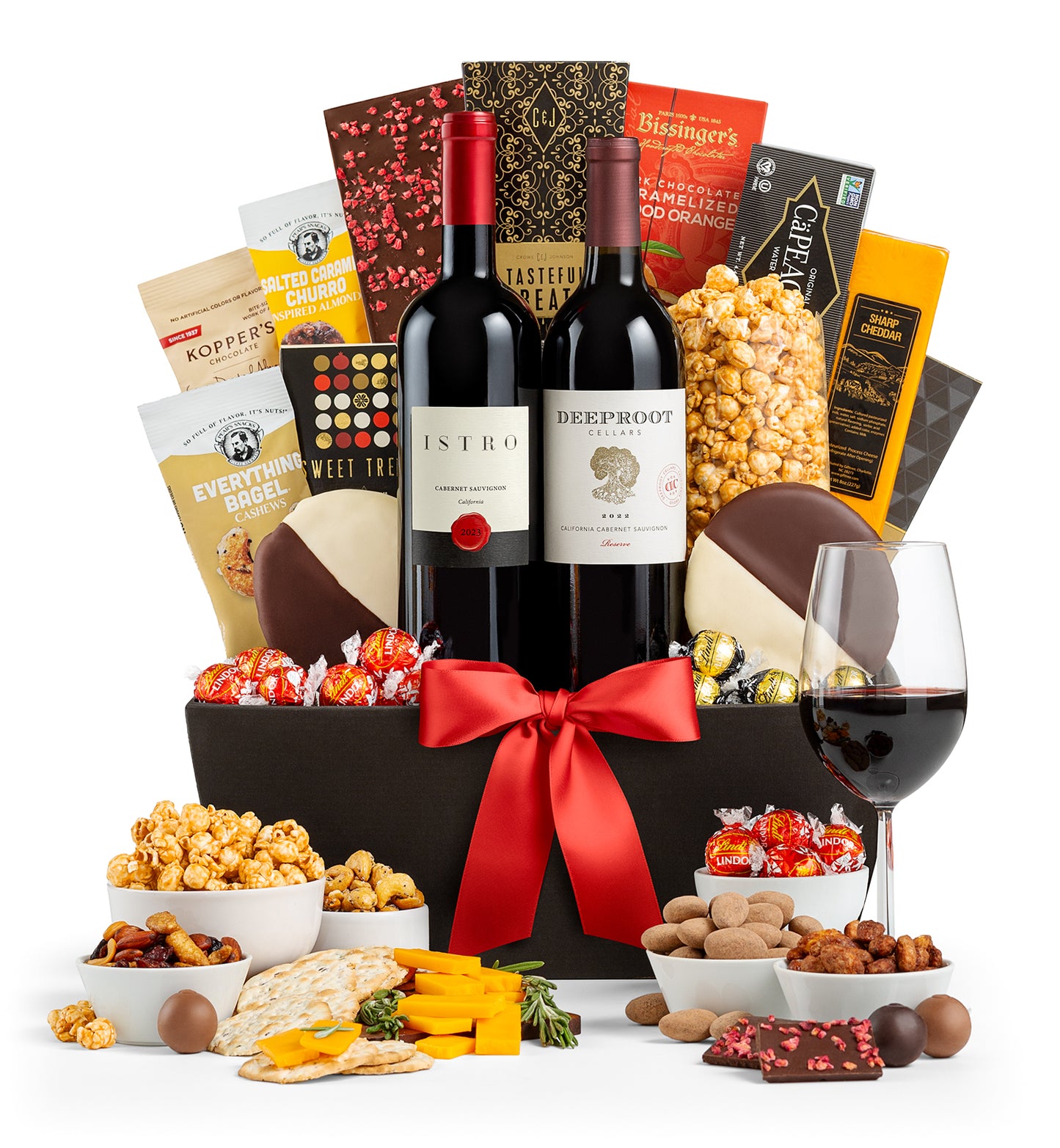 5th Avenue wine basket with snacks, and a glass of red wine on a white background