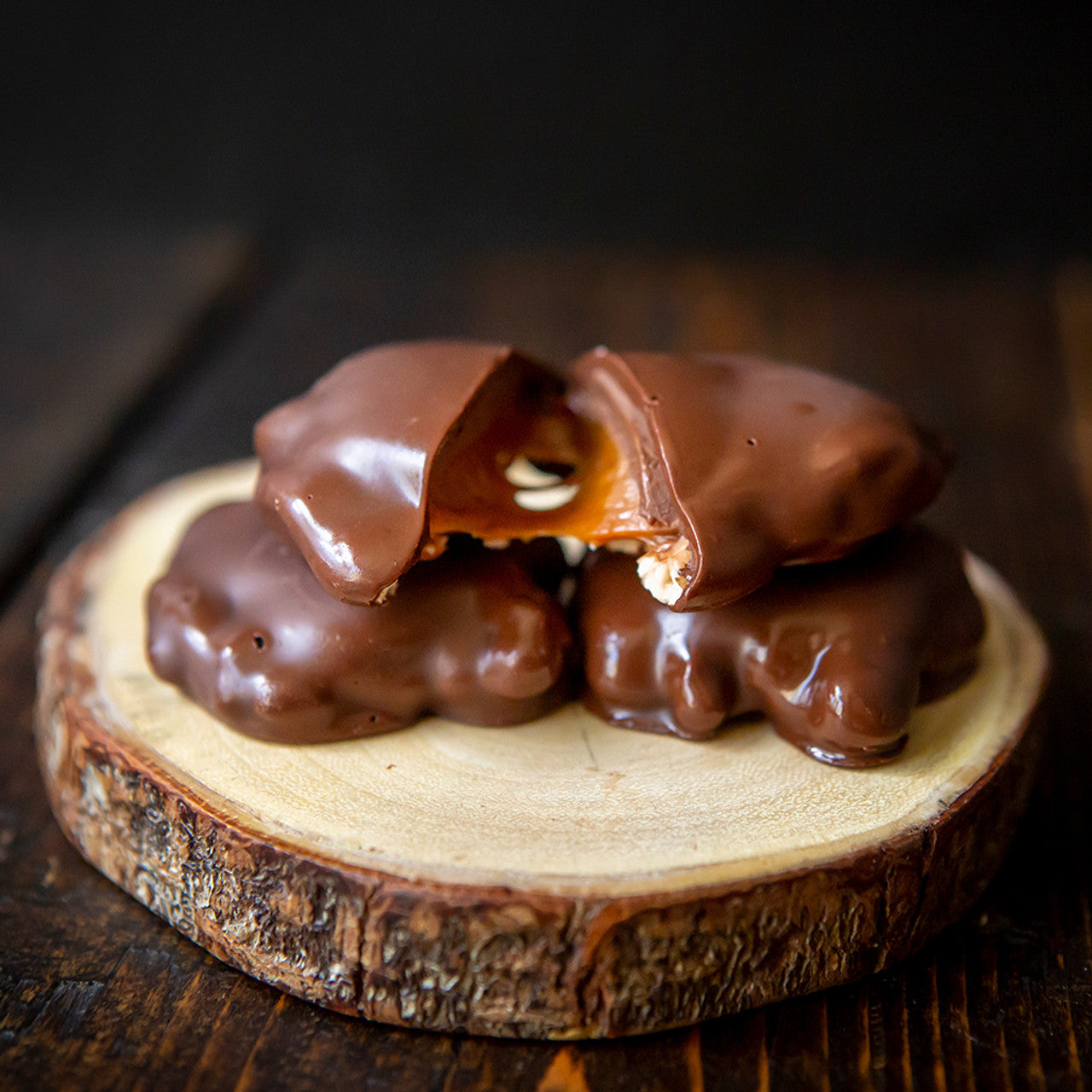Chocolate-covered treats on a wooden coaster with a dark background