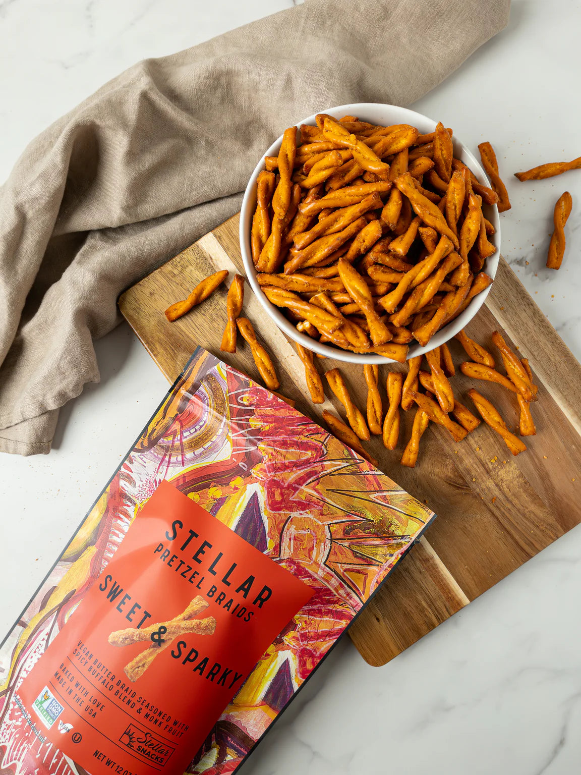 Stellar Sweet & Sparky pretzel sticks in a bowl on a wooden board with packaging.