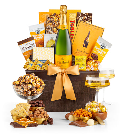 Gourmet gift basket with  Veuve Clicquot champagne, snacks, and chocolates on a white background
