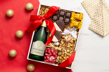 Gift box with Montmore, chocolates, and snacks on a red surface with gold ornaments.