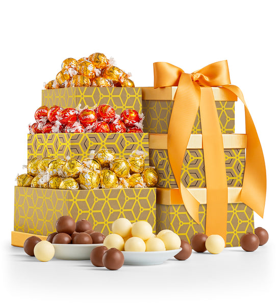 A gift tower consisting of elegantly arranged LINDOR truffles in various chocolate colors, adorned with a golden ribbon.