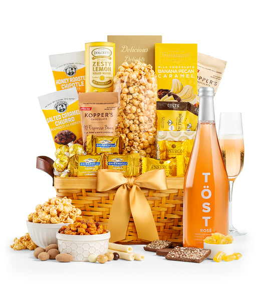 Gourmet gift basket with snacks and a bottle of Töst Sparkling Rosé on a white background