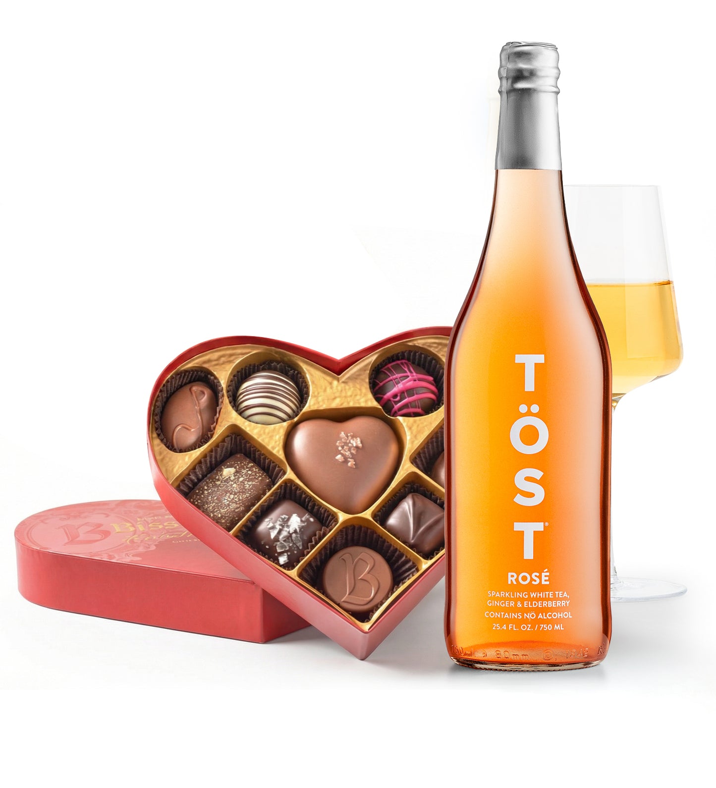 Bottle of Töst rose wine with a heart-shaped chocolate box and a glass of wine on a white background