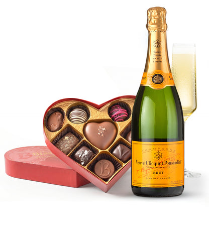 Bottle of Veuve Clicquot champagne with a heart-shaped chocolate box on a white background