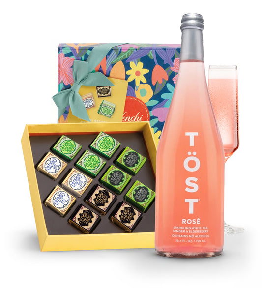 Bottle of Töst Rosé, box of chocolates, and glass of pink drink on a white background