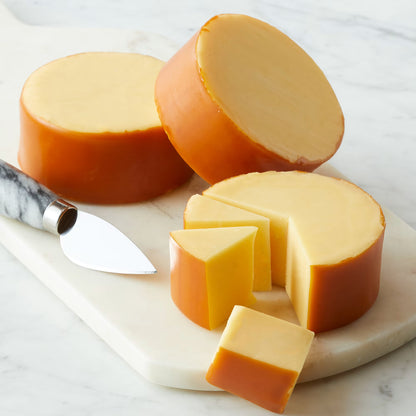Two round pieces of cheese with a knife on a marble surface