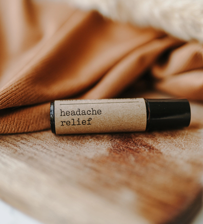 Roller bottle labeled 'headache relief' on a wooden surface with a brown fabric background