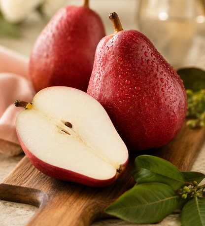 Red pears with one sliced open on a wooden cutting board.